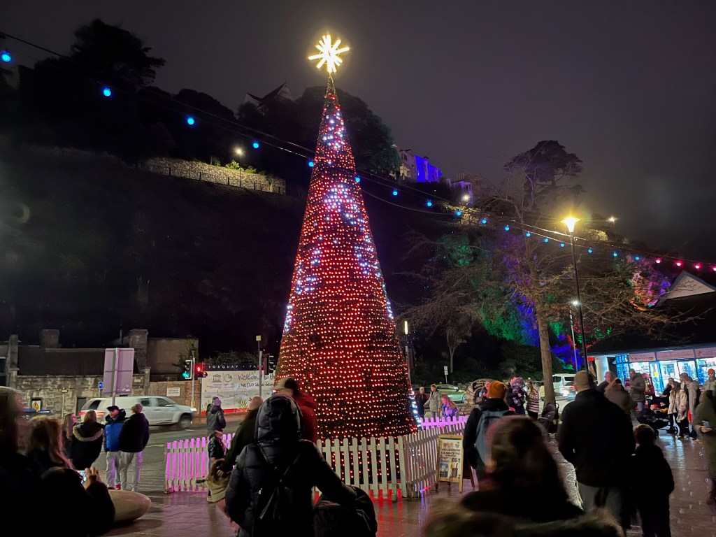 A very tall tree-like structure, covered in pixels that are showing animated red and white patterns. A brightly lit yellow star sits on top of the tree.
