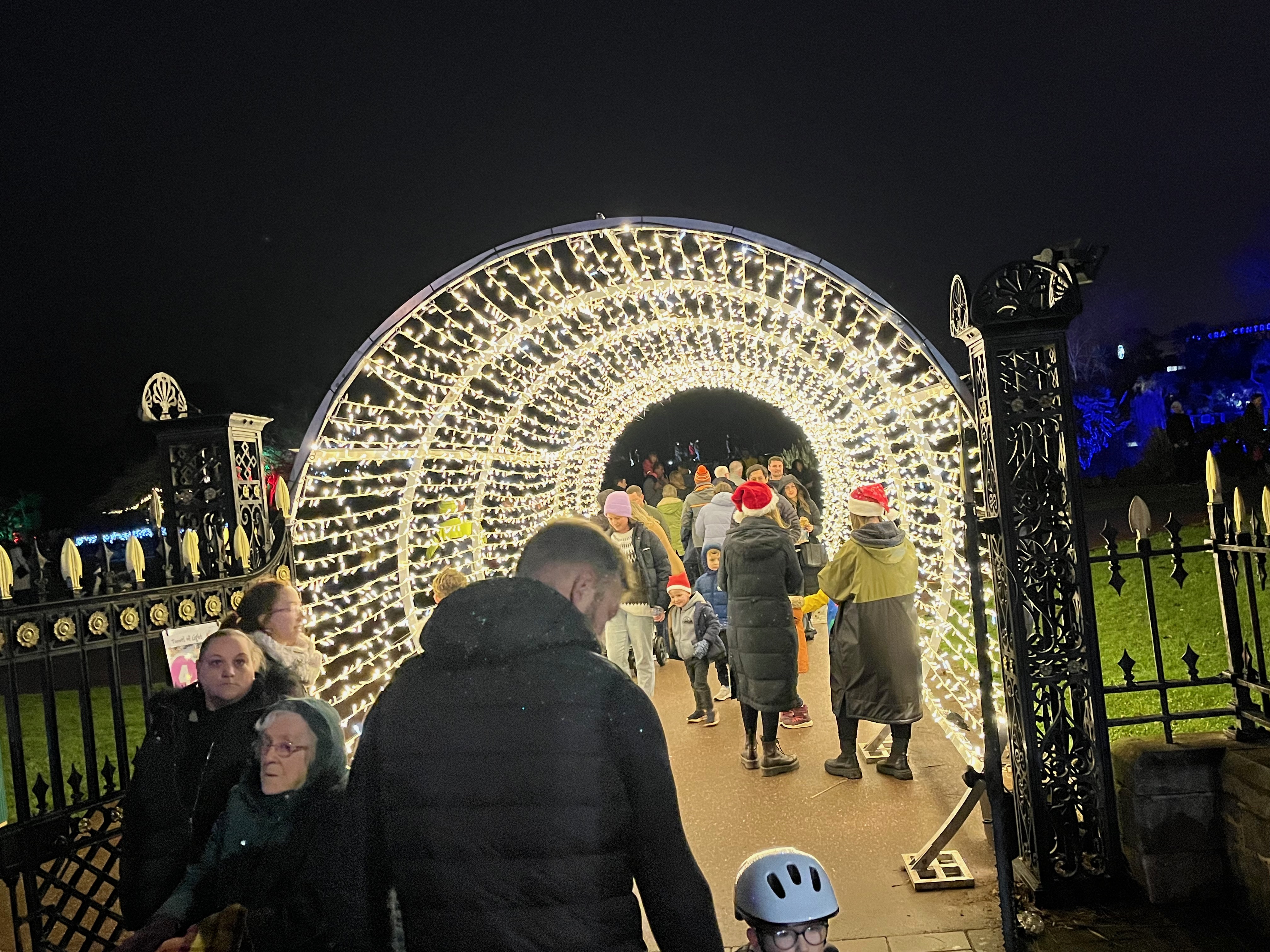 People walking through a tunnel of bright festive lights in Abbey Park in Torquay.