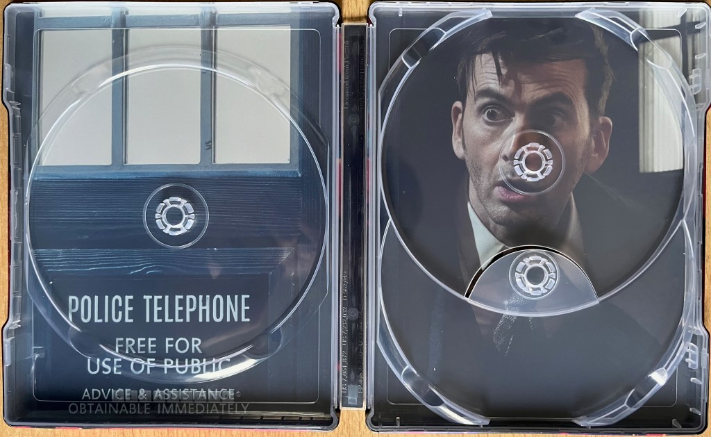 The interior spread of the Doctor Who 60th Anniversary specials Blu-ray steelbook, behind where the discs are stored, showing David Tennant's Doctor looking out of the door of the Tardis with a concerned expression on his face.