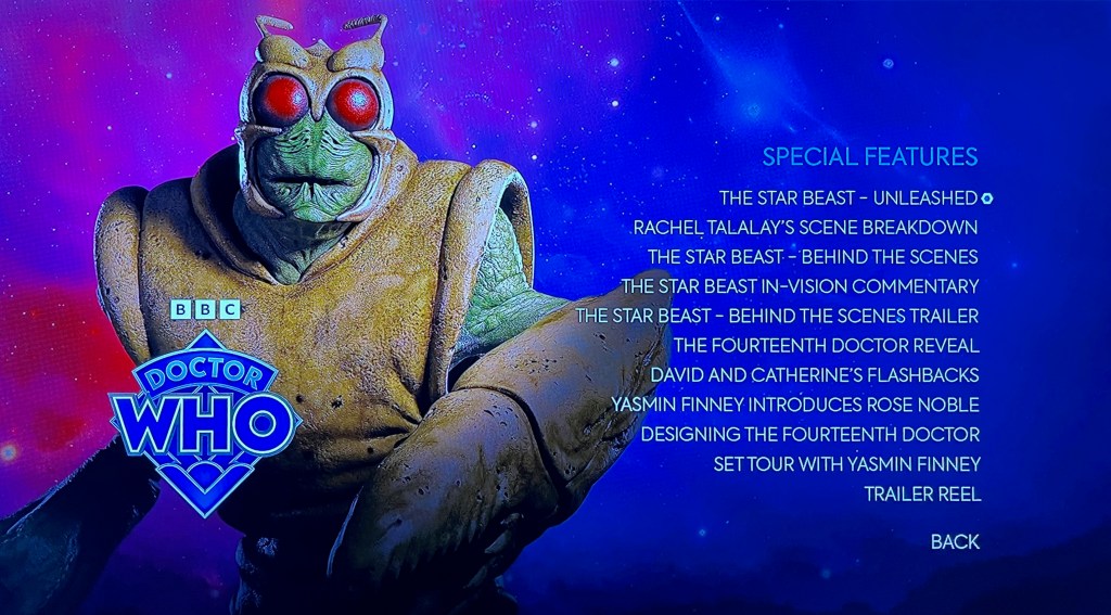 Special Features menu for The Star Beat, in the Doctor Who 60th anniversary Specials Blu-ray. The menu shows the options to choose from, alongside a Wrarth Warrior, a large green alien with big red eyes. The Doctor Who logo is in the bottom left corner.