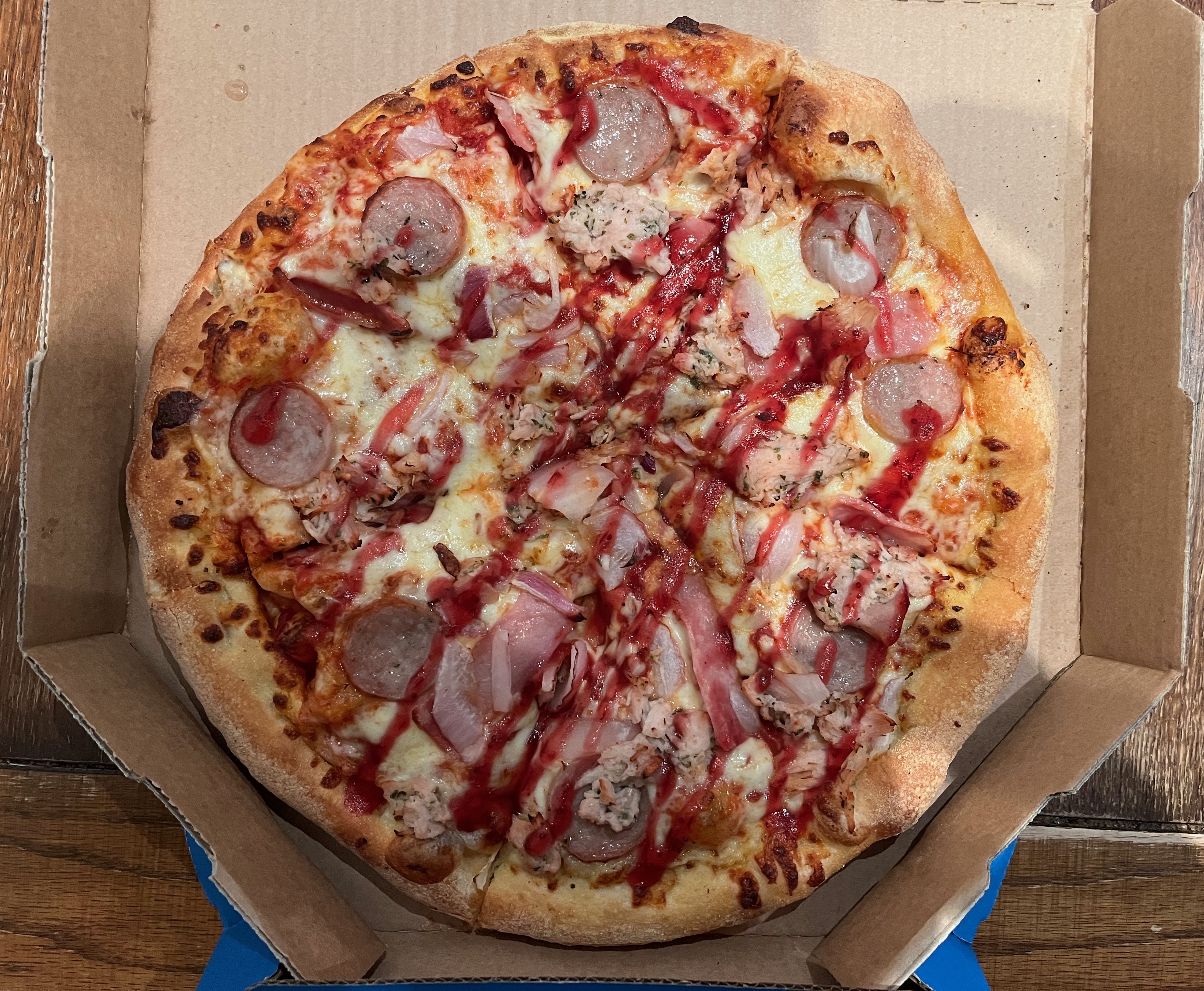The Festive One pizza from Domino's, with pulled sage & onion turkey, sausage, smoked bacon, onions and mozzarella cheese, with zigzag lines of cranberry drizzle over the top.