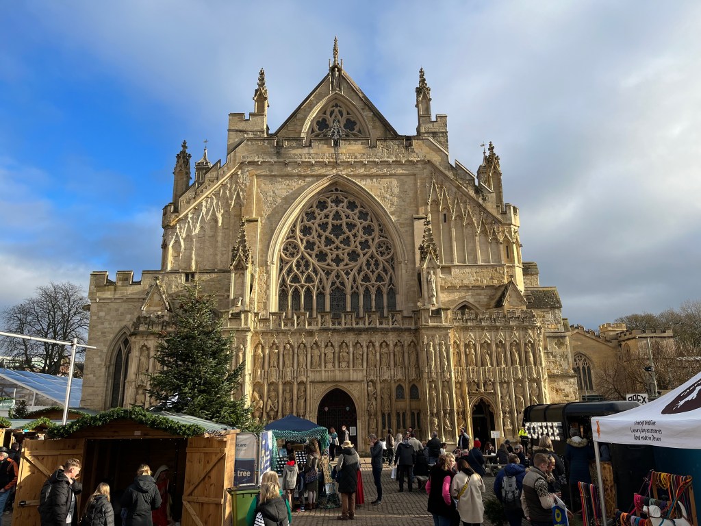 The front of Exeter Cathedral, towering over the people browsing the Christmas market stalls.
