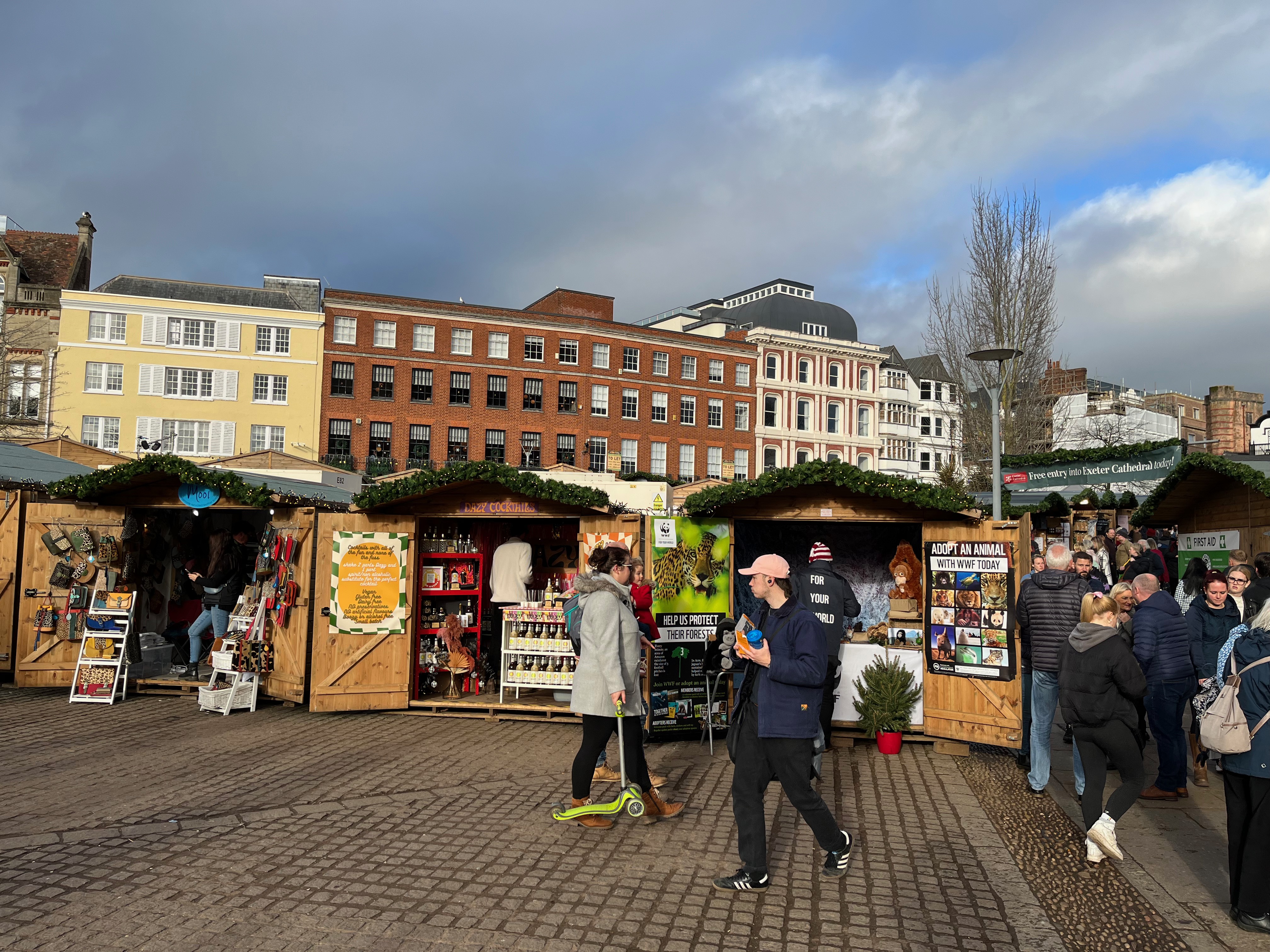 People browsing stalls at Exeter Cathedral's Christmas Market, including one selling cocktails, and another promoting the WWF charity.