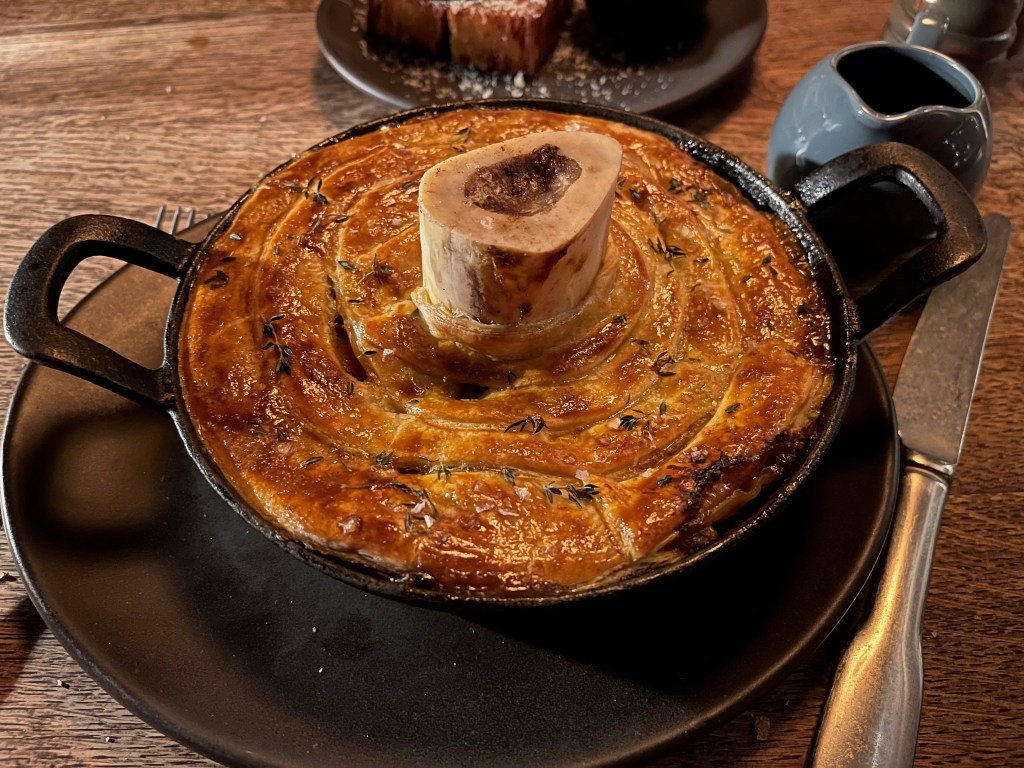 A big dish filled with a puff pastry pie, with a thick bone filled with marrow standing in the centre, at the In Horto restaurant.