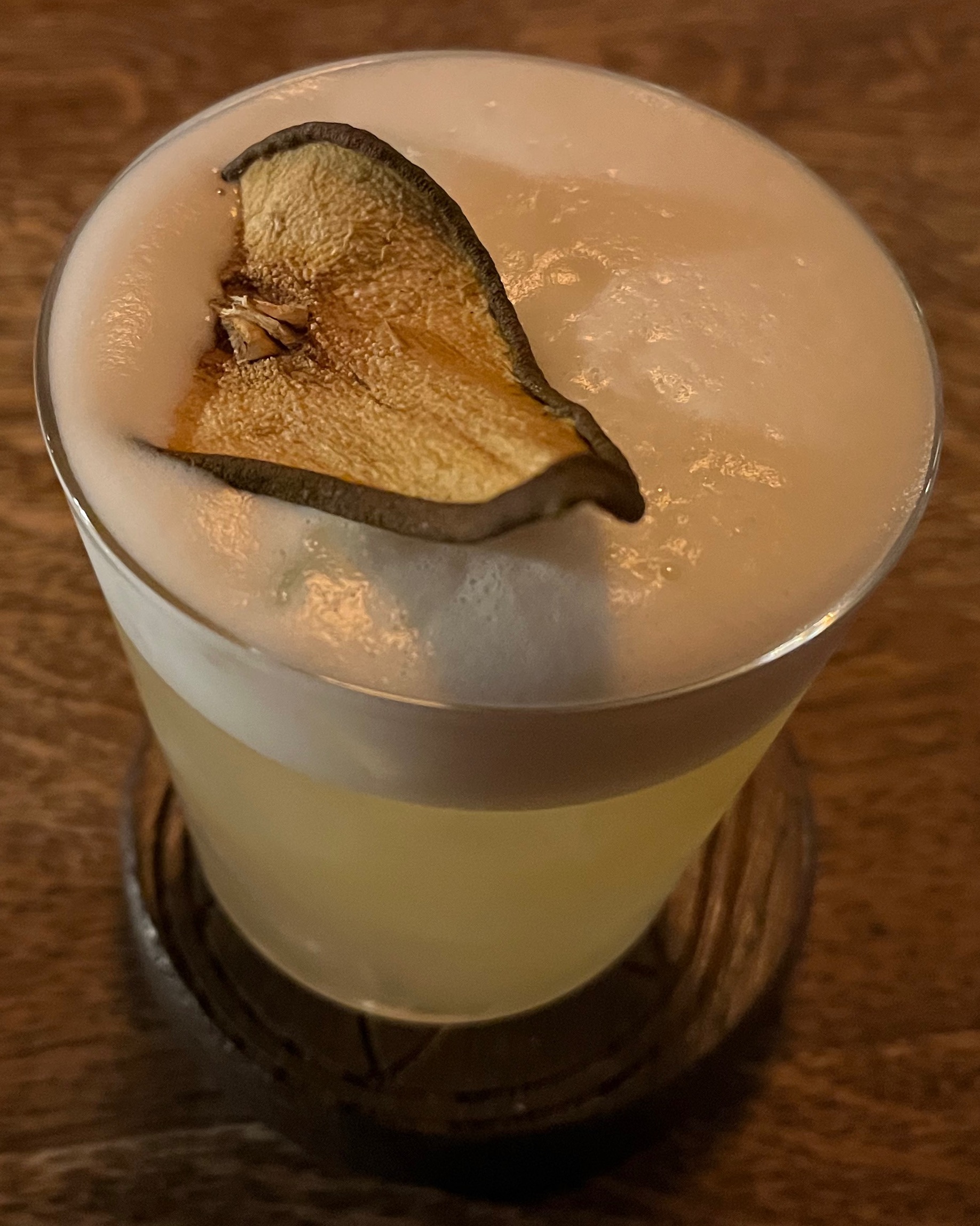 A pear sour cocktail, with a white foamy head on the top.