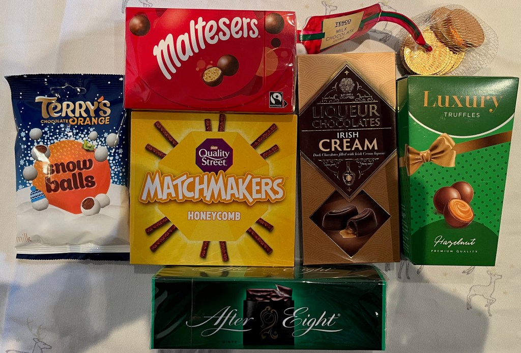 A collection of treats including Terry's Chocolate Orange Snowballs, Maltesers, Quality Street Honeycomb Matchmakers, Tesco Milk Chocolate Coins, Irish Cream Liqueur Chocolates, Luxury Hazelnut Truffles, and After Eight Mints.
