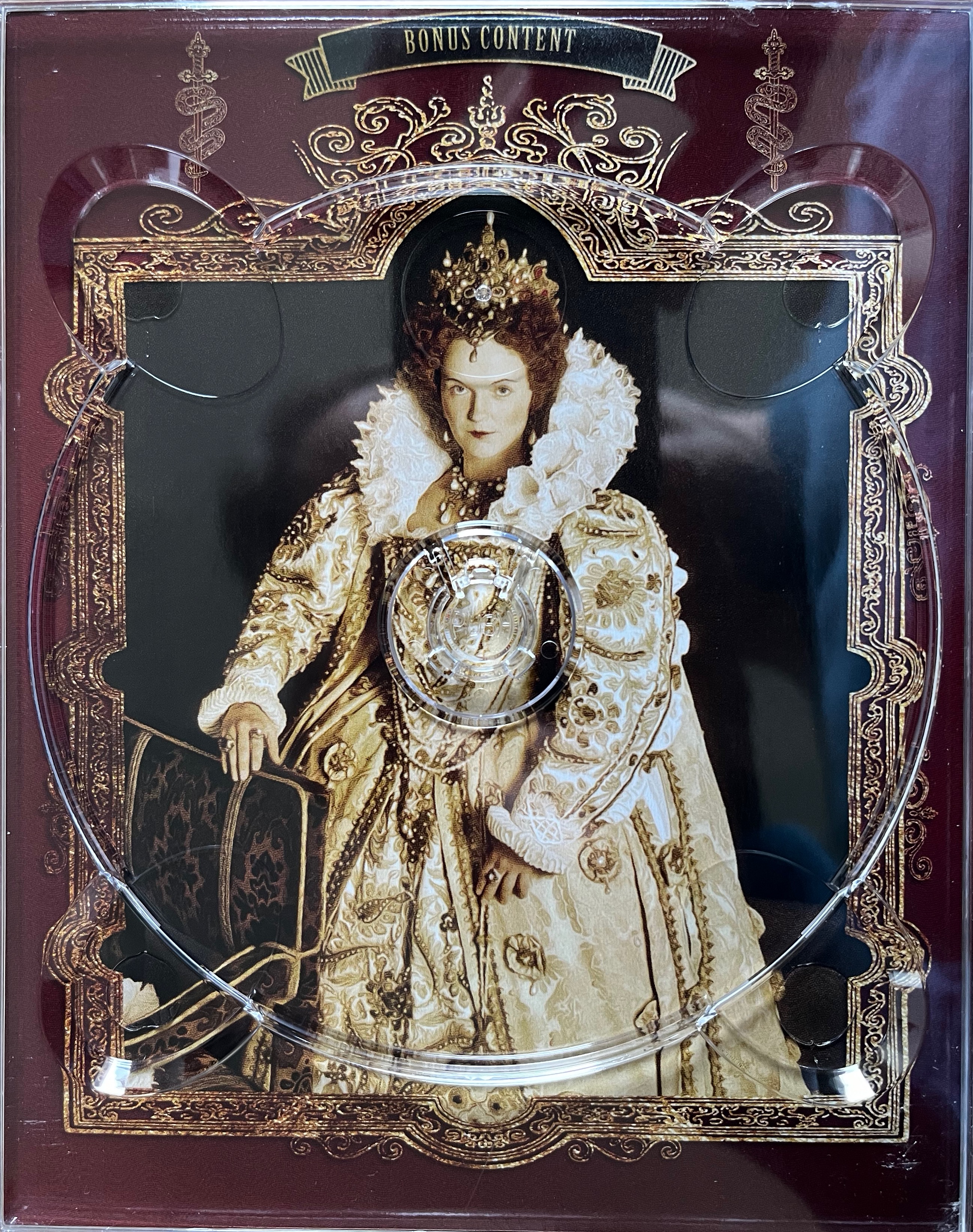 Artwork behind the disc holder for the Bonus Content disc in the Blackadder Complete Collection Blu-ray box set, featuring a large image of Queen Elizabeth from Series 2, surrounded by an ornate gold frame.
