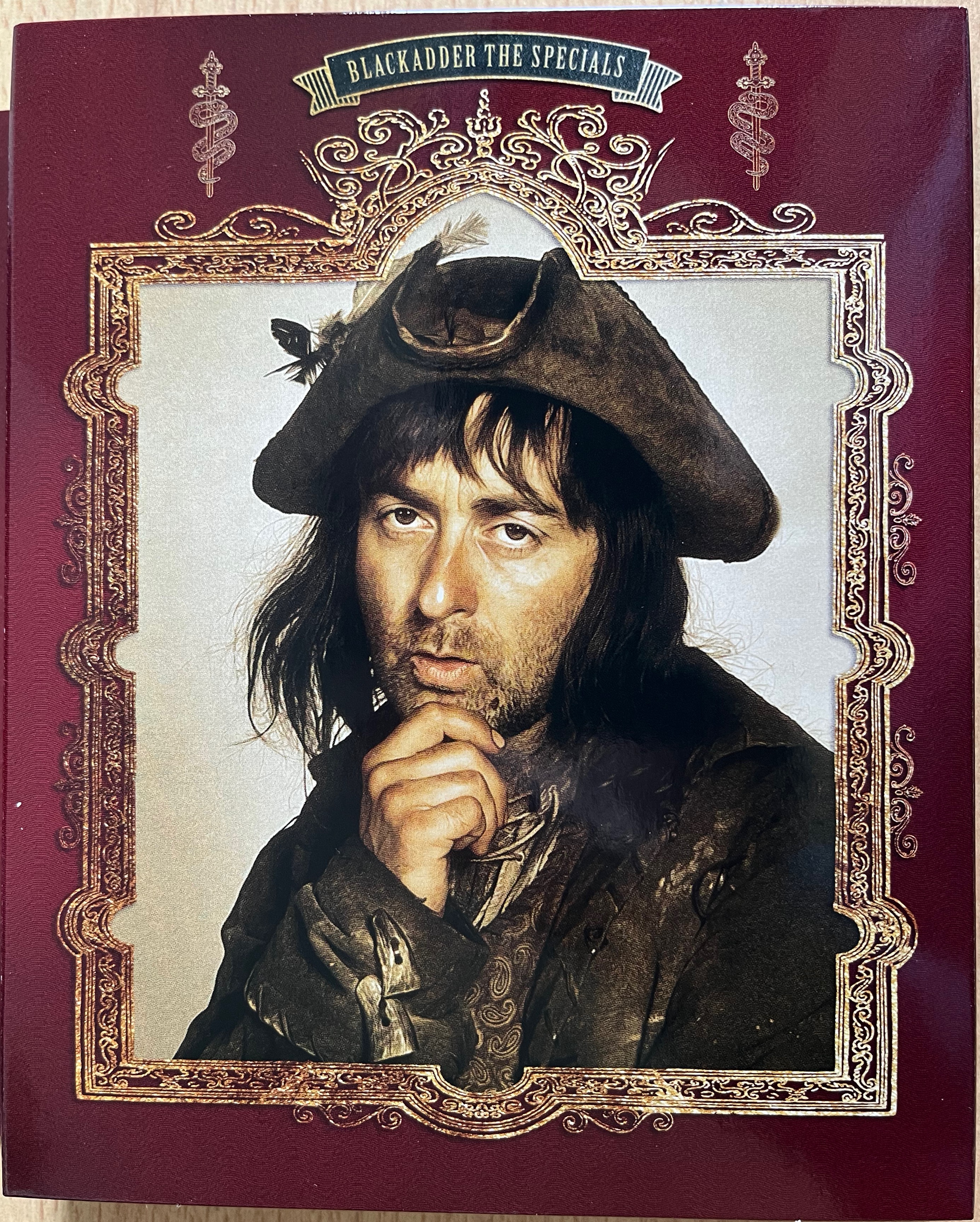 Cover art for the Specials disc in the Blackadder Complete Collection Blu-ray box set, featuring a large image of Baldrick surrounded by an ornate gold frame.