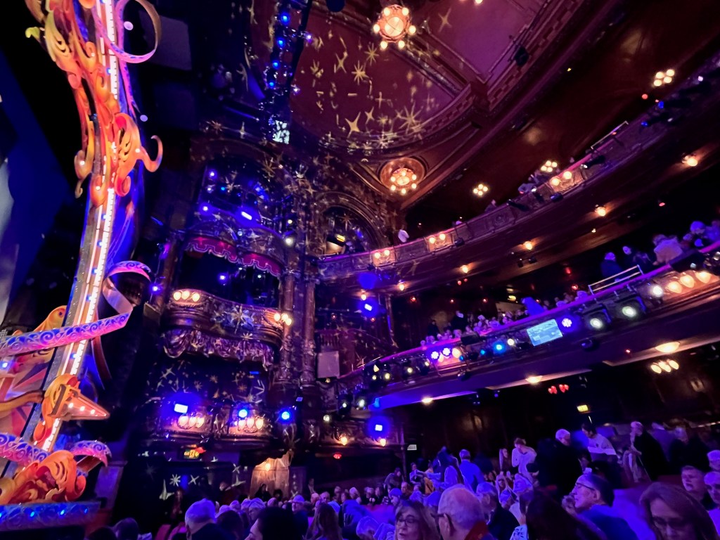 The auditorium in the Palladium for the Peter Pan pantomime, mixing blue lighting with the more traditional lights, and stars projected on the walls.