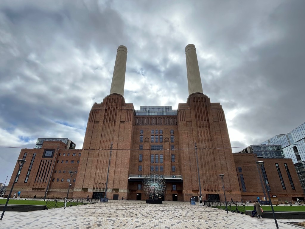 Front view of Battersea Power Station, with its two tall white chimneys on the left and right towers.