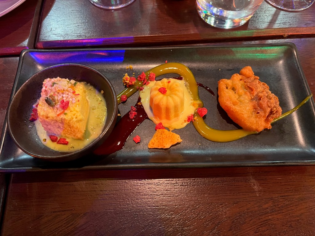 A narrow rectangular tray with a trio of small but colourful desserts, at the Cinnamon Kitchen Holi Feast.