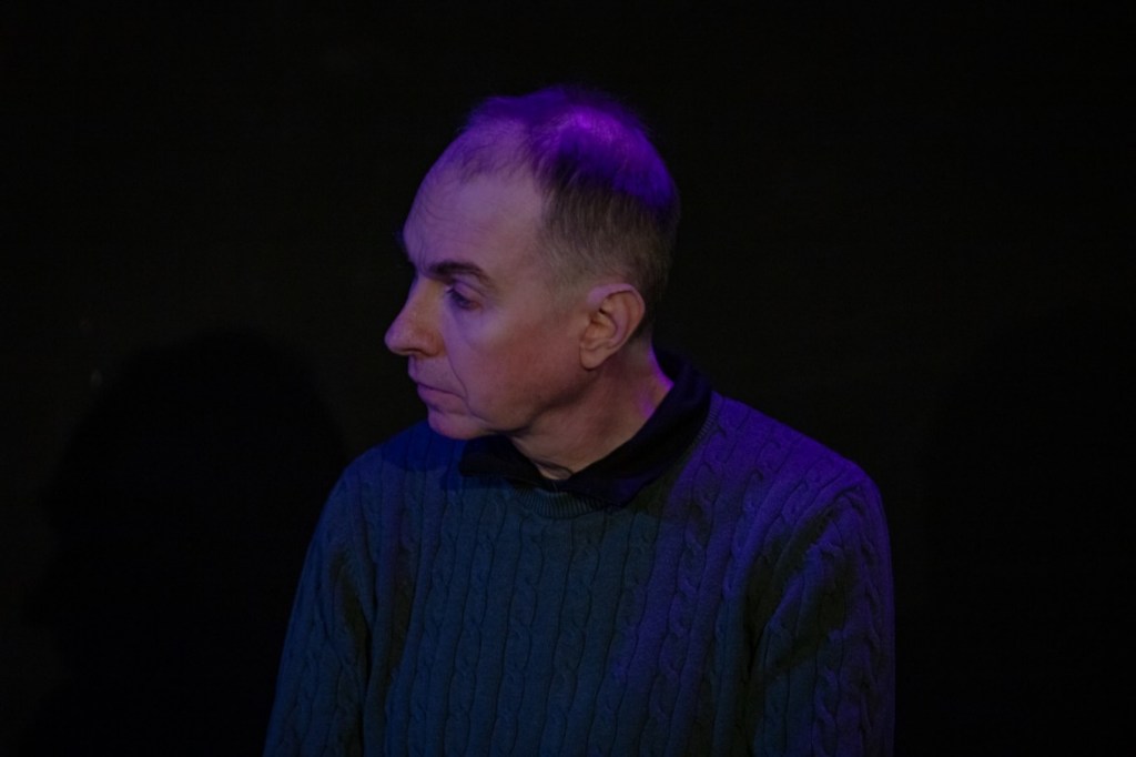Ian Rattray, a white man with short brown hair, wears a blue sweater and looks to his right.