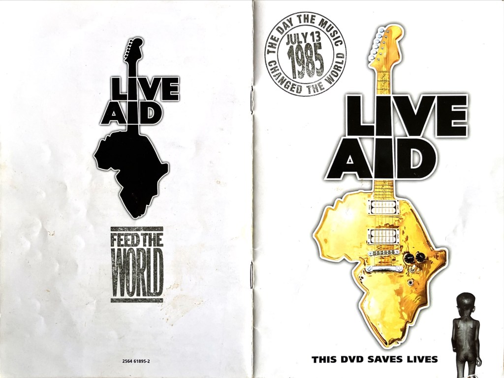 Cover spread for the Live Aid DVD booklet. The front shows a guitar, the body of which is shaped like Africa. Large black letters across the neck of the guitar spell Live Aid, one word above the other, with the two letter I's lining up with the guitar neck. A circle at the top left of the page, made to look like it's been rubber-stamped, has the text The Day The Music Changed The World around its edge, and the date July 13 1985 in the centre. At the bottom right of the page, next to the text This DVD Saves Lives below the guitar, is an image of a naked, malnourished, black child, viewed from the back. The back cover, meanwhile, has a silhouette image of the same guitar logo, above text that says Feed The World.