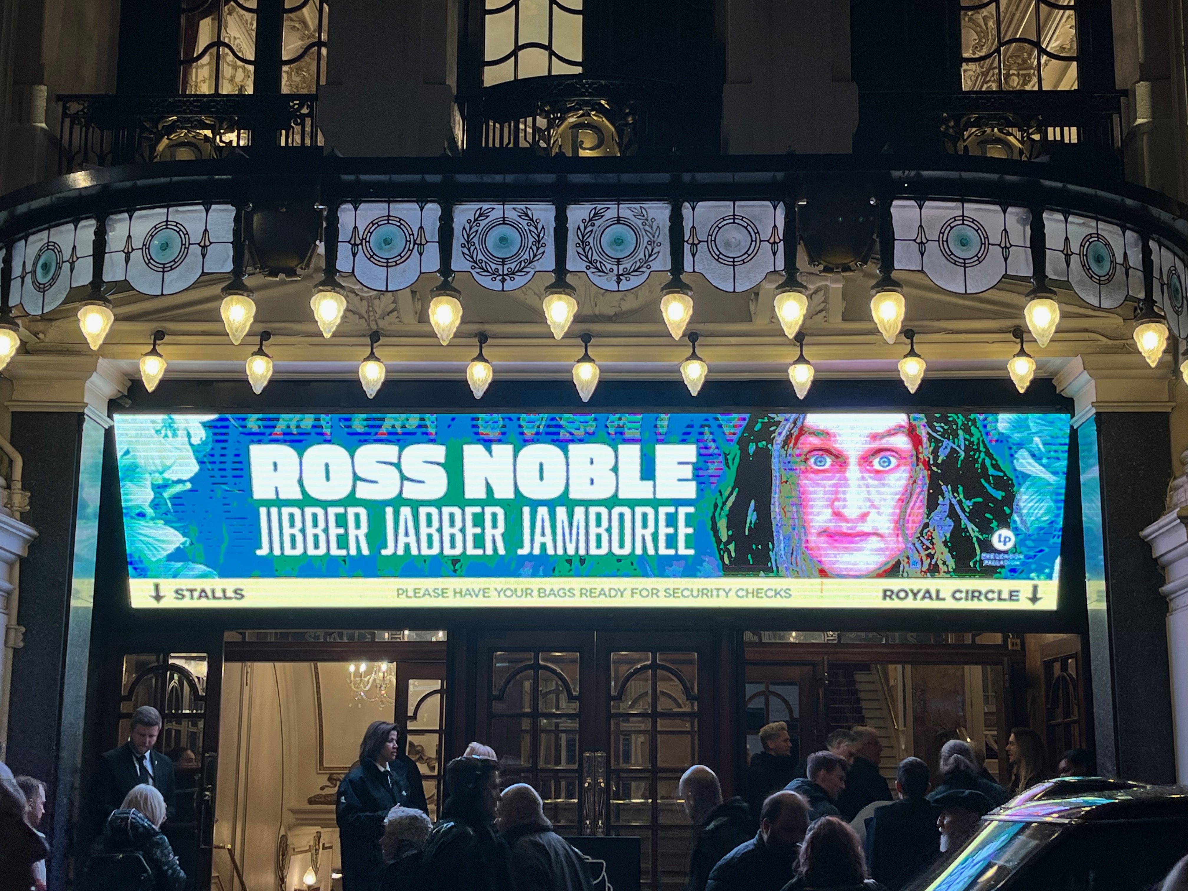 Screen showing the title Ross Noble, Jibber Jabber Jamboree, with the text next to a photo of Ross Noble's face, above the entrance to the London Palladium.