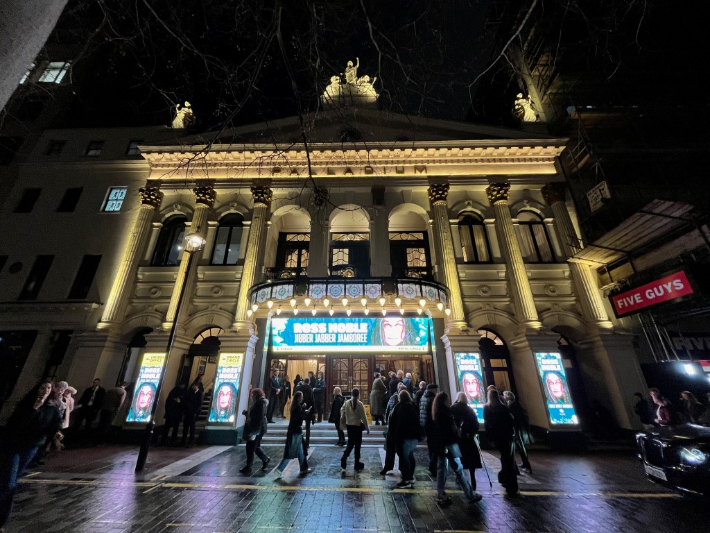 The London Palladium lit up at night, advertising Ross Noble's show Jibber Jabber Jamboree on the ground floor and above the entrance.