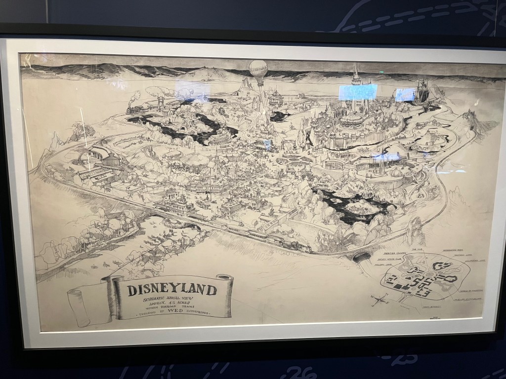 A large and heavily detailed black and white drawing showing an aerial view of the vast expanse of Disneyland. A caption at the bottom reads Disneyland, schematic aerial view, approximately 45 acres, within railroad tracks, designed by W.E.D. Enterprises.