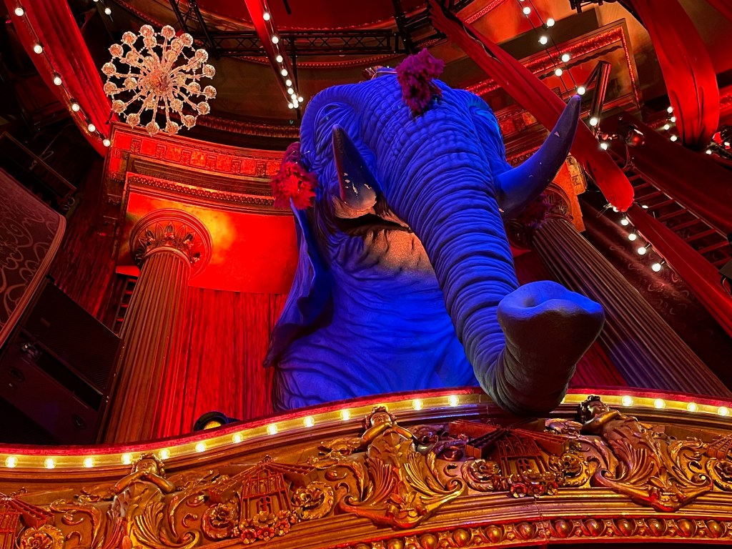 A large model of a blue elephant in the upper circle of the auditorium for the Moulin Rouge musical, its trunk hanging over the edge of the balcony.