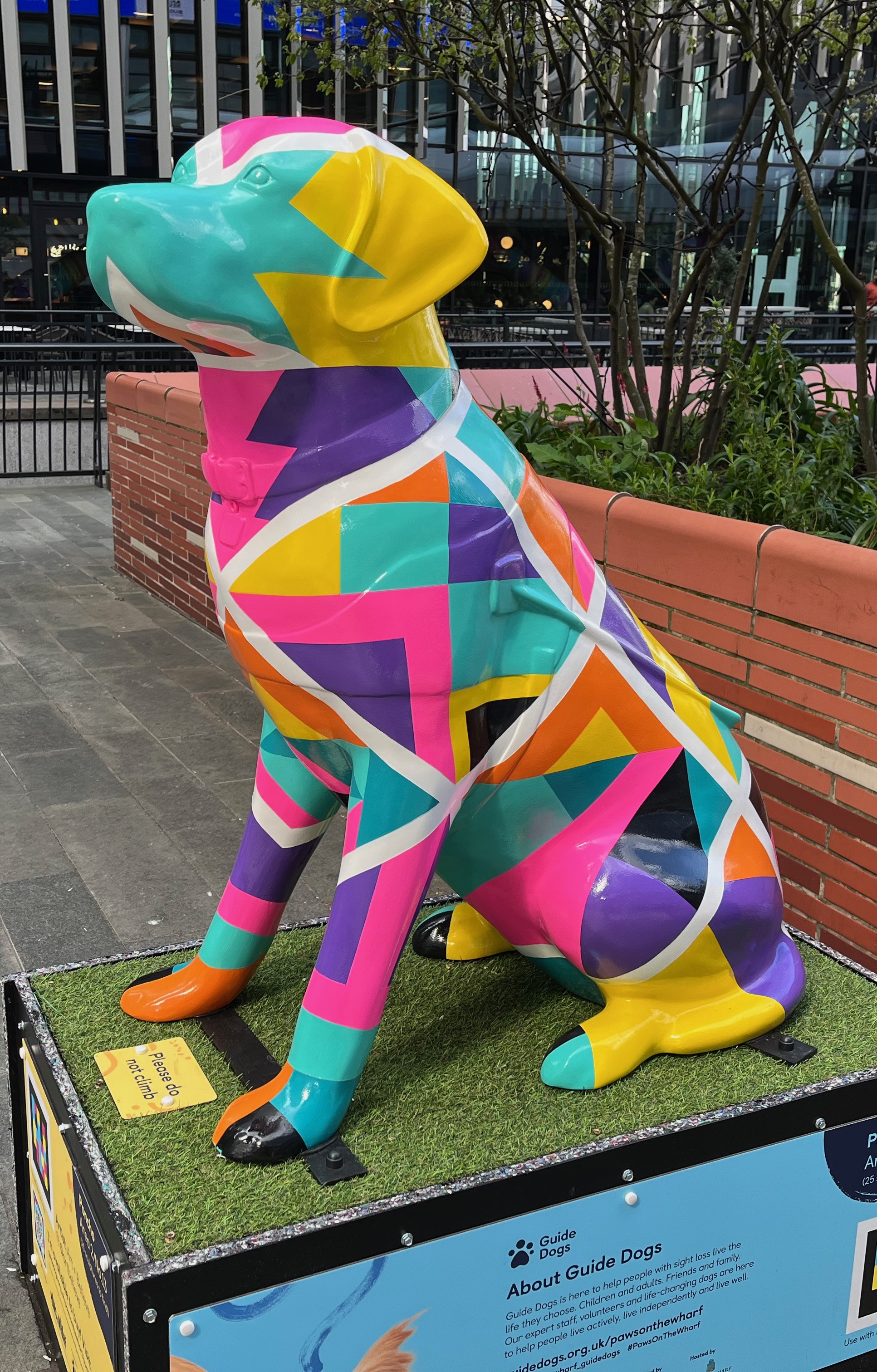Left side view of a guide dog sculpture covered with a colourful and vibrant geometric design inspired by Southern American ponchos.