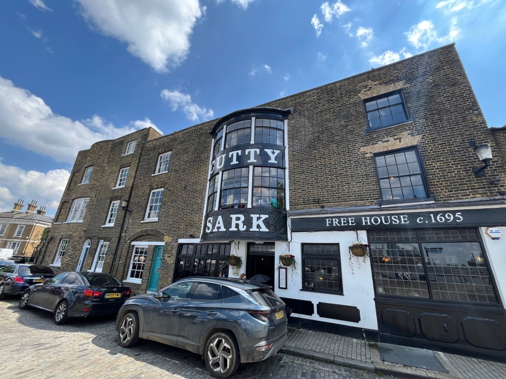 The Cutty Sark Pub. The name is written in big white letters on a black background, between windows that bulge out from the upper two floors in the centre of the building.