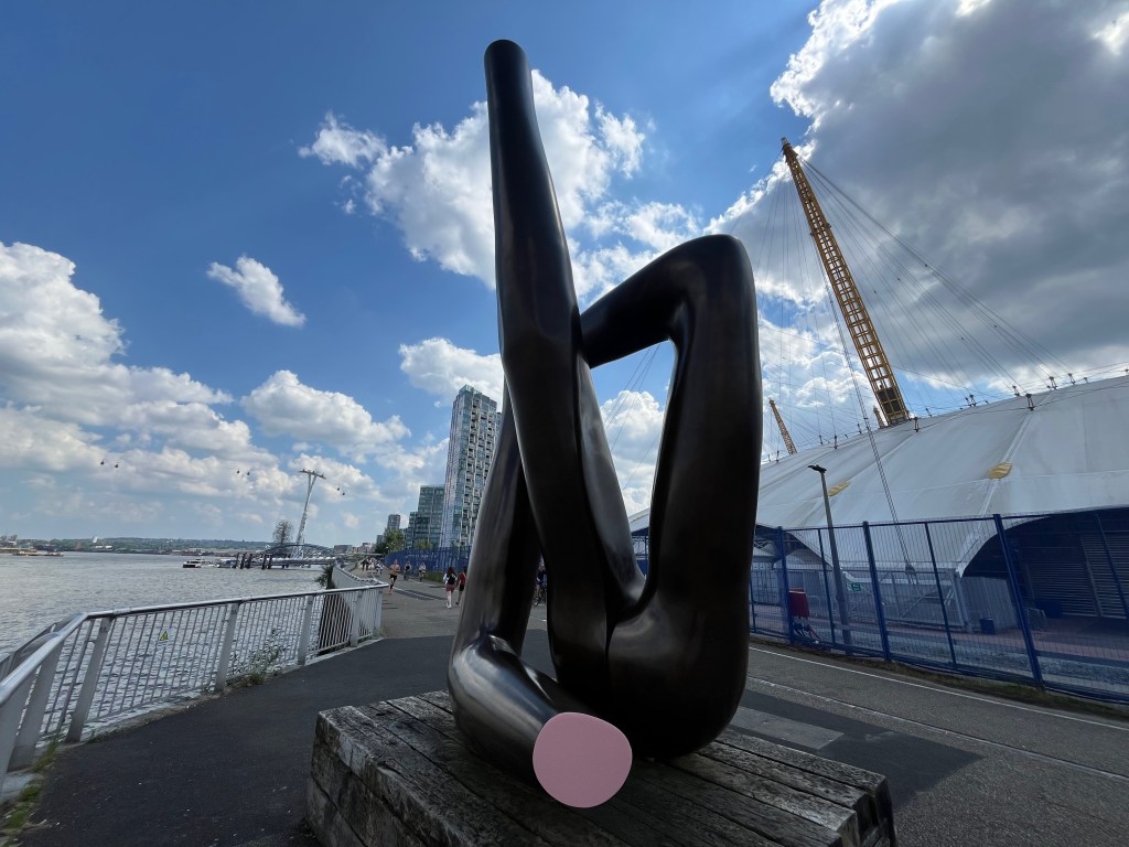 Public artwork called Liberty Grip by Gary Hume. It's made of 3 large black structures that are a bit like the arms of mannequins. One of these stands straight up in the air, while the other 2 are bent at the elbows and are arranged to form an approximate square shape around the central structure.