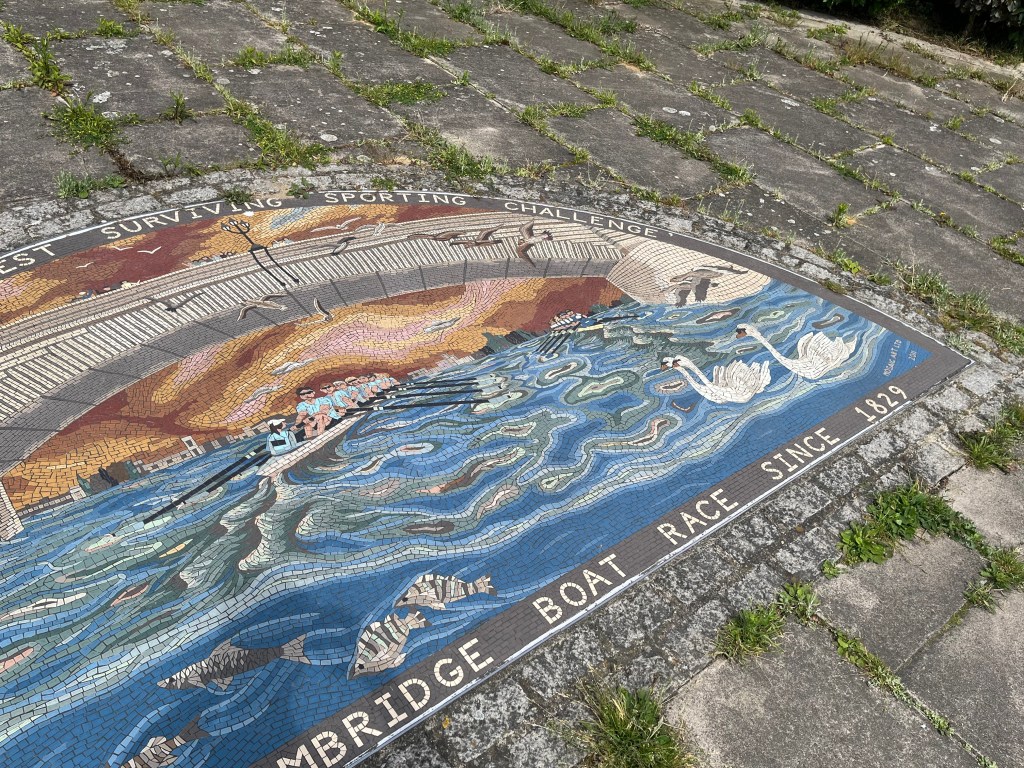 The right side of the Oxford and Cambridge Boat Race mural, showing one of the teams rowing under a bridge, while a few swans float by on the water and a couple of other birds fly above them.