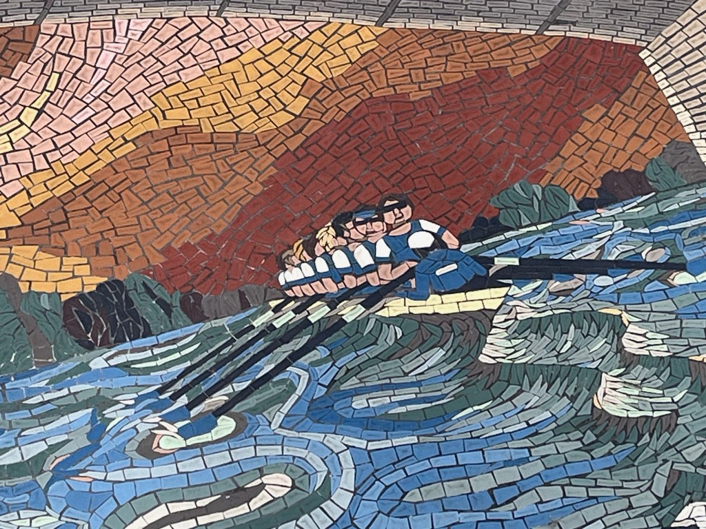 Close-up of the Oxford team of rowers in the Oxford and Cambridge Boat Race mural, wearing dark blue shirts.