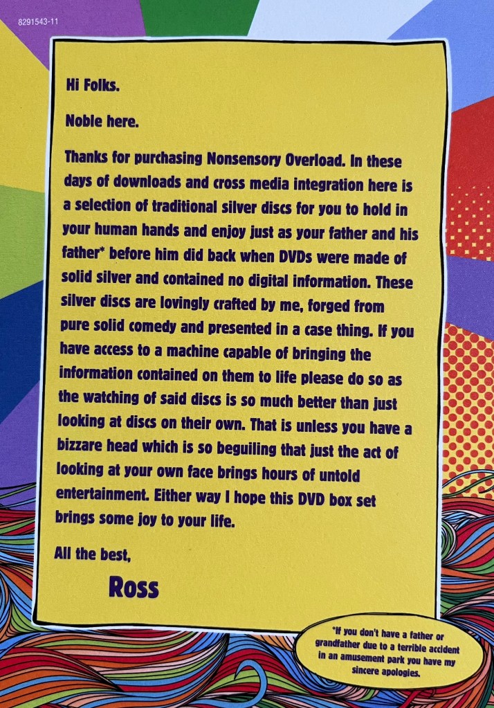 Message by Ross Noble on a card with his Nonsensory Overload DVD, in dark blue on a yellow background. It says Hi Folks, Noble here. Thanks for purchasing Nonsensory Overload. In these days of downloads and cross media integration here is a selection of traditional silver discs for you to hold in your human hands and enjoy just as your father and his father before him did back when DVDs were made of solid silver and contained no digital information. These silver discs are lovingly crafted by me, forged from pure solid comedy and presented in a case thing. If you have access to a machine capable of bringing the information contained on them to life please do so as the watching of said discs is so much better than just looking at discs on their own. That is unless you have a bizarre head which is so beguiling that just the act of looking at your own face brings hours of untold entertainment. Either way I hope this DVD box set brings some joy to your life. All the best, Ross. P.S. If you don't have a father or grandfather due to a terrible accident in an amusement park you have my sincere apologies.