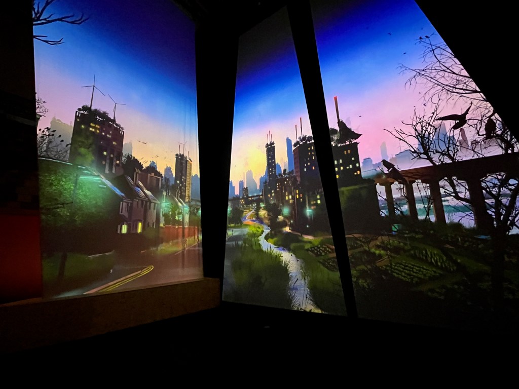 A large floor to ceiling animated display spanning two walls around a corner, showing birds inhabiting a residential street that has houses on one side and a winding stream with greenery on its banks on the other side of the road. The stream weaves its way towards skyscrapers in the distance.