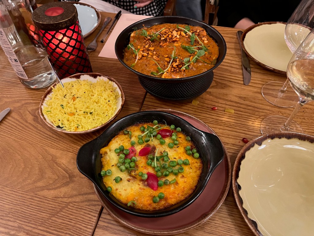 3 dishes of food at the Cinnamon Bazaar restaurant, one of which has some yellow rice.