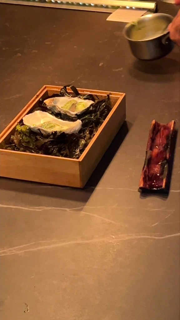 2 oysters in their shells with a white sauce added to them, presented in the kitchen at the Ekstedt At The Yard restaurant.