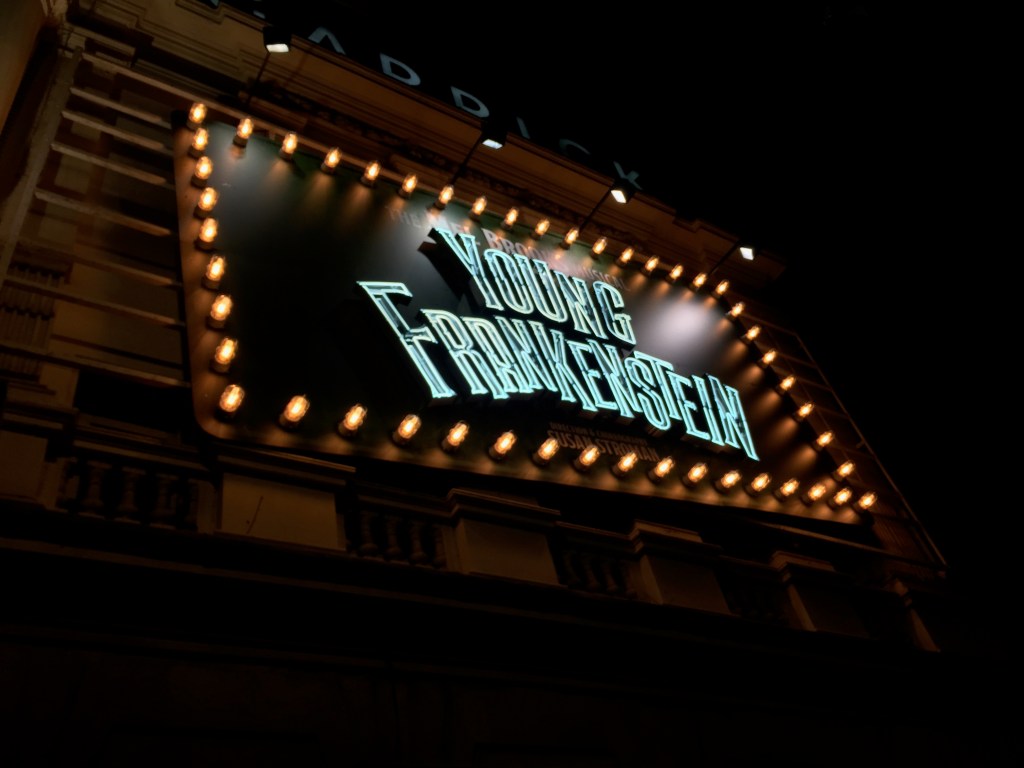 The words Young Frankenstein lit up on a big sign outside the Garrick Theatre, with lots of small lights all around the edge of the sign.