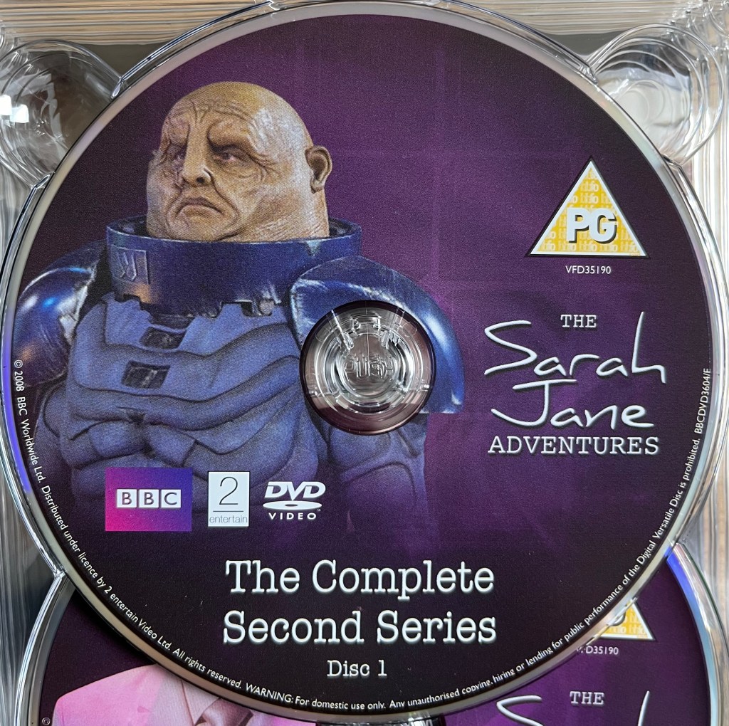 Series 2 Disc 1 from the DVD box set of The Sarah Jane Adventures, including a photo of a Sontaran with its helmet removed so we see its potato-like head.