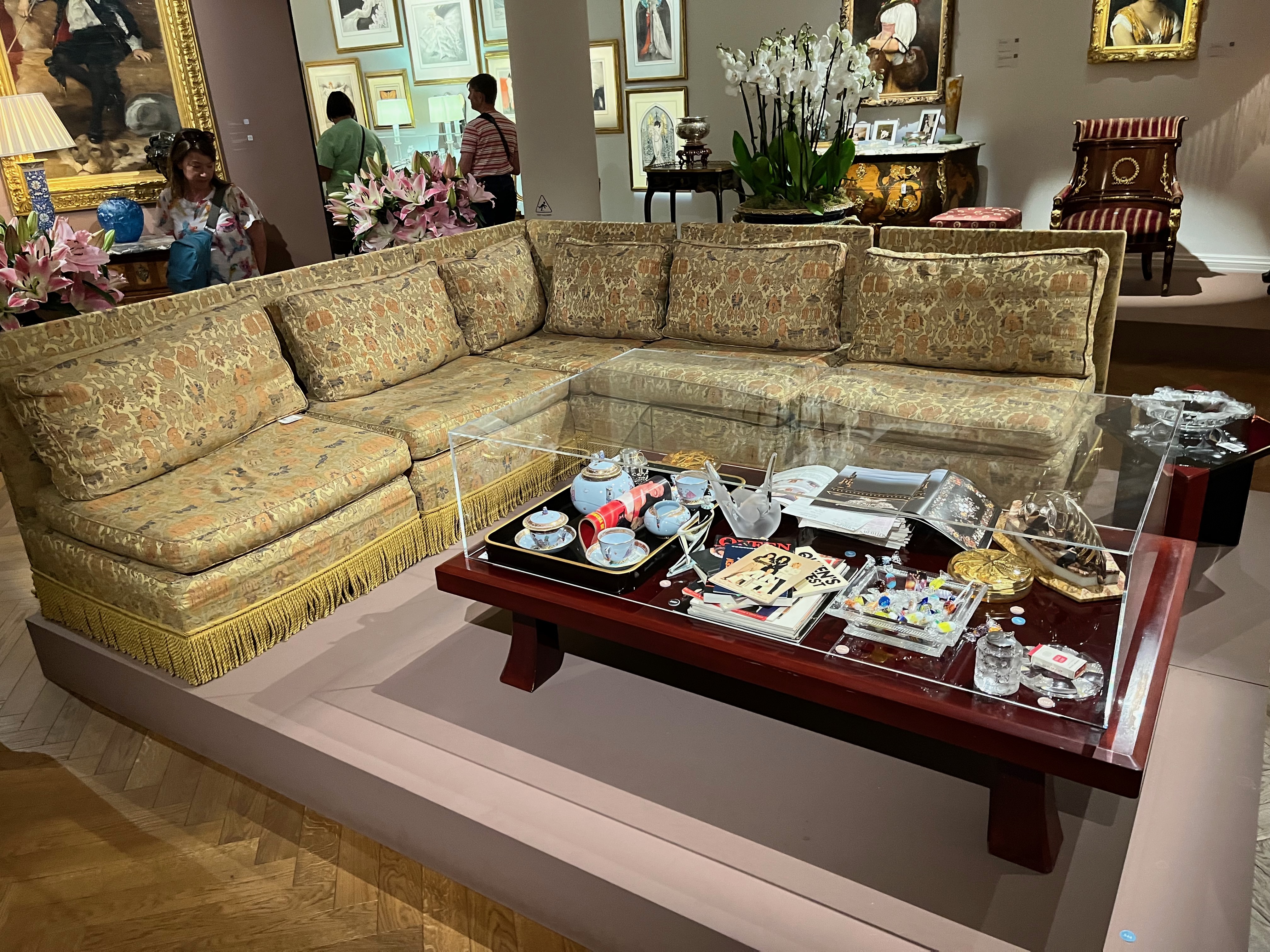 A large 5-seater L-shaped settee covered in ornately decorated gold fabric.