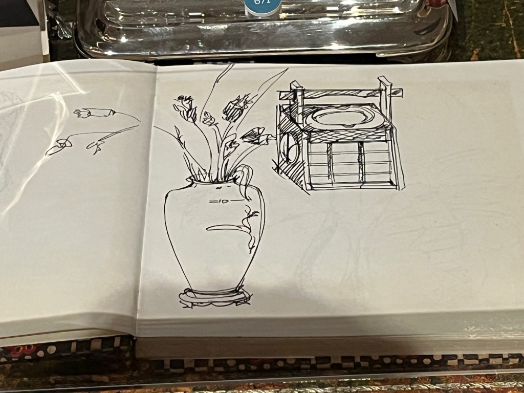 Freddie Mercury's sketchbook, open to a page with a drawing of a flowers in a vase and an item of furniture.