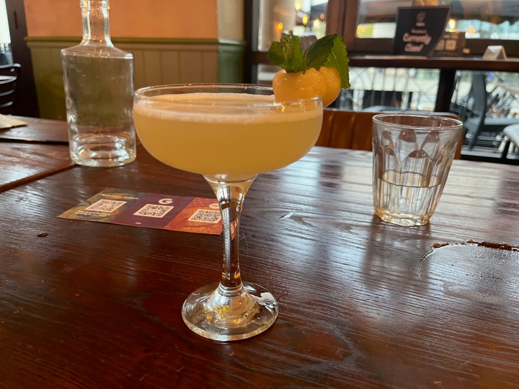 Lychee martini cocktail, with a lychee perched on the rim of the shallow glass.