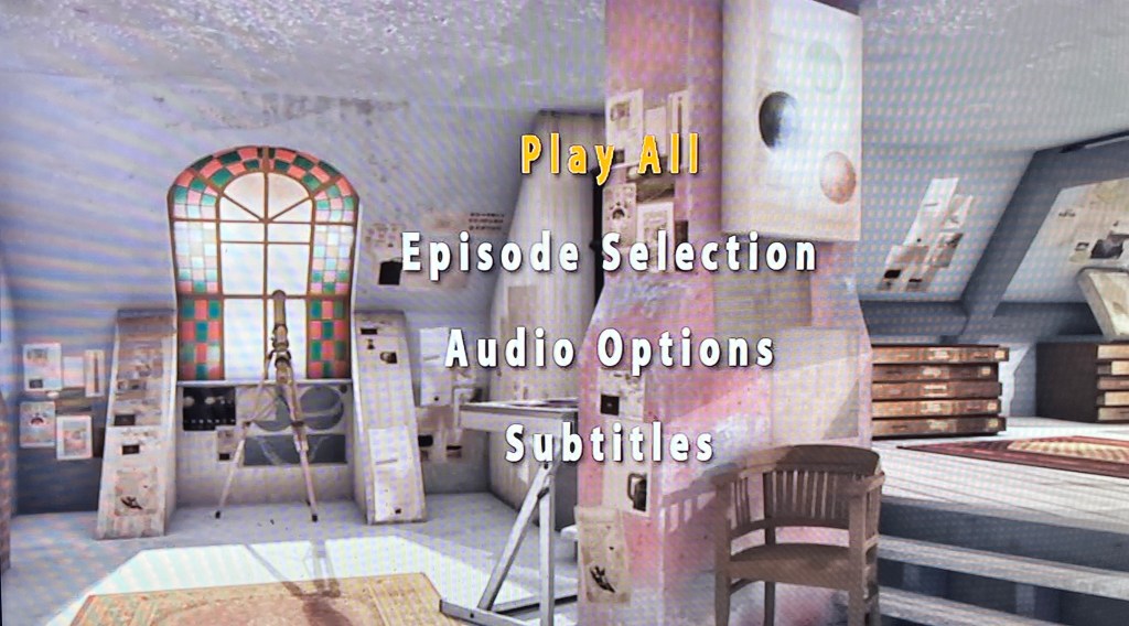 The audio navigation main menu on the DVD for Series 4 of The Sarah Jane Adventures. The attic from the show is in the background, but with the colour removed so it's in greyscale. The 4 options - Play All, Episode Selection, Audio Options and Subtitles - are presented in large, clear white lettering down the centre of the screen, with the currently selected option highlighted in yellow text.