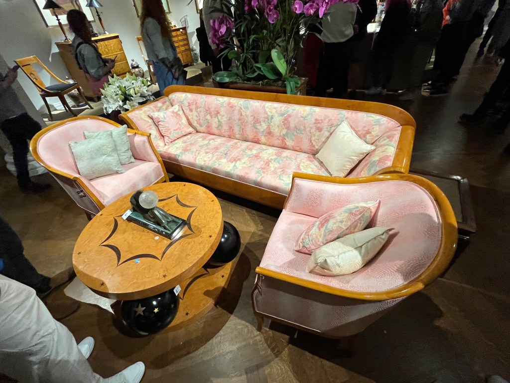 A suite of 2 tub style armchairs with rounded backs and a 3-seater sofa, covered in a pink silk fabric with a snakeskin style floral pattern.