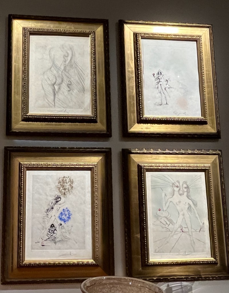 A set of 4 sketches by surrealist Salvador Dali, mainly black and white but with occasional elements of colour. It's hard to determine exactly what they're meant to show, though one appears to show a female figure with 2 heads, and instead of faces the heads each have a hole in the centre from which black lines are spraying out.