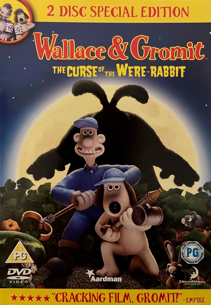 The front cover of the DVD for Wallace And Gromit, The Curse Of The Were-Rabbit. It shows Wallace in a blue hat and uniform holding a long pincer device, and Gromit wearing a blue hat as he hold a large spray gun, while a large silhouette of a rabbit towers over them in front of the moon in the background.