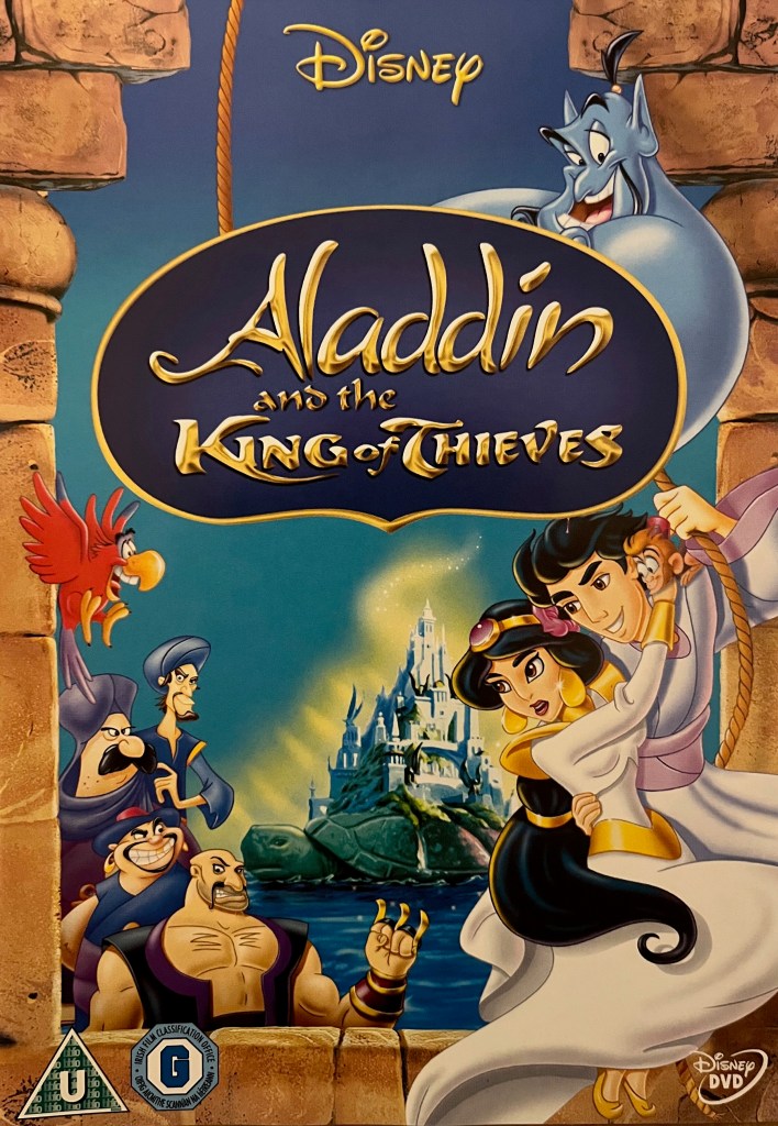 Front cover for the DVD of Aladdin And The King Of Thieves. Below the movie's title, Aladdin and Princess Jasmine fly away from the palace together, holding on to a rope held by the big blue genie. To their left, red parrot Iago flies over four of the thieves, who look strong and menacing.