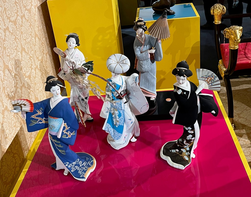 A collection of 5 Japanese Hakata clay dolls, depicting Japanese ladies in colourful robes, two of whom are holding fans while another holds an unopened umbrella.