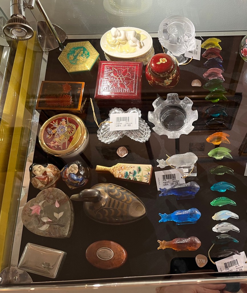 A glass case in the Freddie Mercury exhibition with various items, including lidded boxes along with figures of deer and fish.