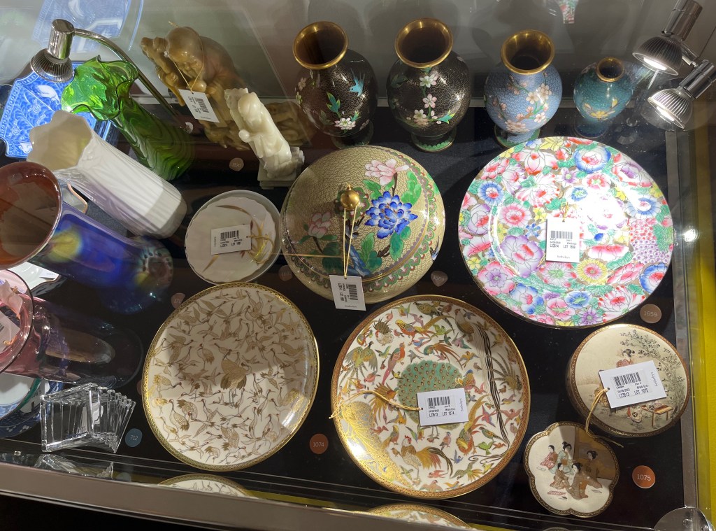 A glass case in the Freddie Mercury exhibition with various items, including vases, Chinese figurines and enamel wares, and Japanese dishes.