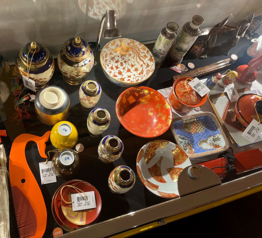A selection of small Japanese objects in a glass case in the Freddie Mercury exhibition, including vases, tea bowls and cups.