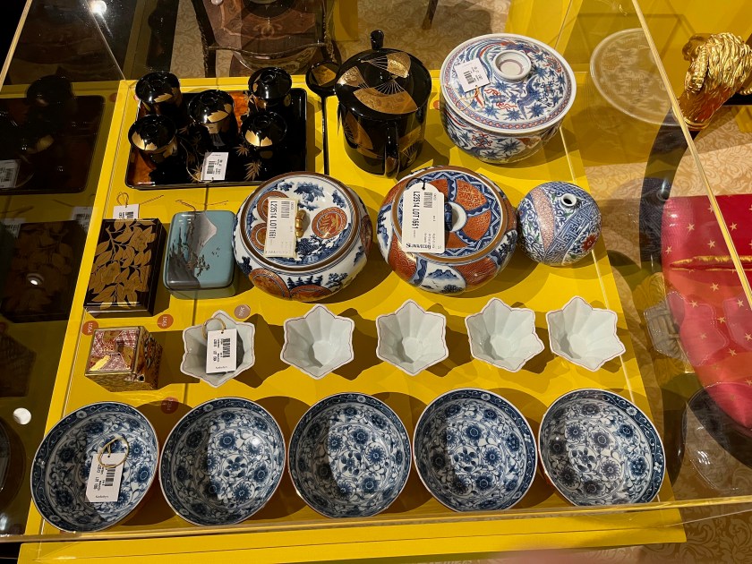 A selection of small objects in a glass case in the Freddie Mercury exhibition, including bowls, plates and vases.