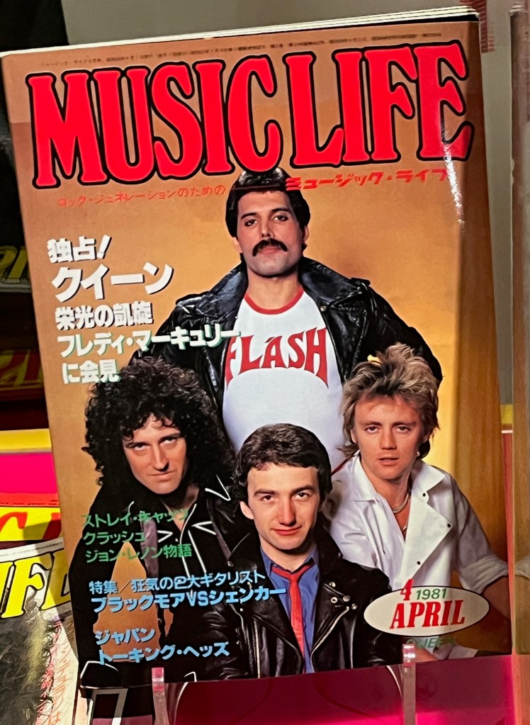 An edition of the Japanese magazine Music Life from 4 April 1981. The cover shows an image of the band Queen. Freddie Mercury is standing at the back with his hands on his hips, his leather jacket opened to reveal the Flash logo from Flash Gordon on his white t-shirt. Fellow band members Brian, John and Roger are posing together lower down in front of him.