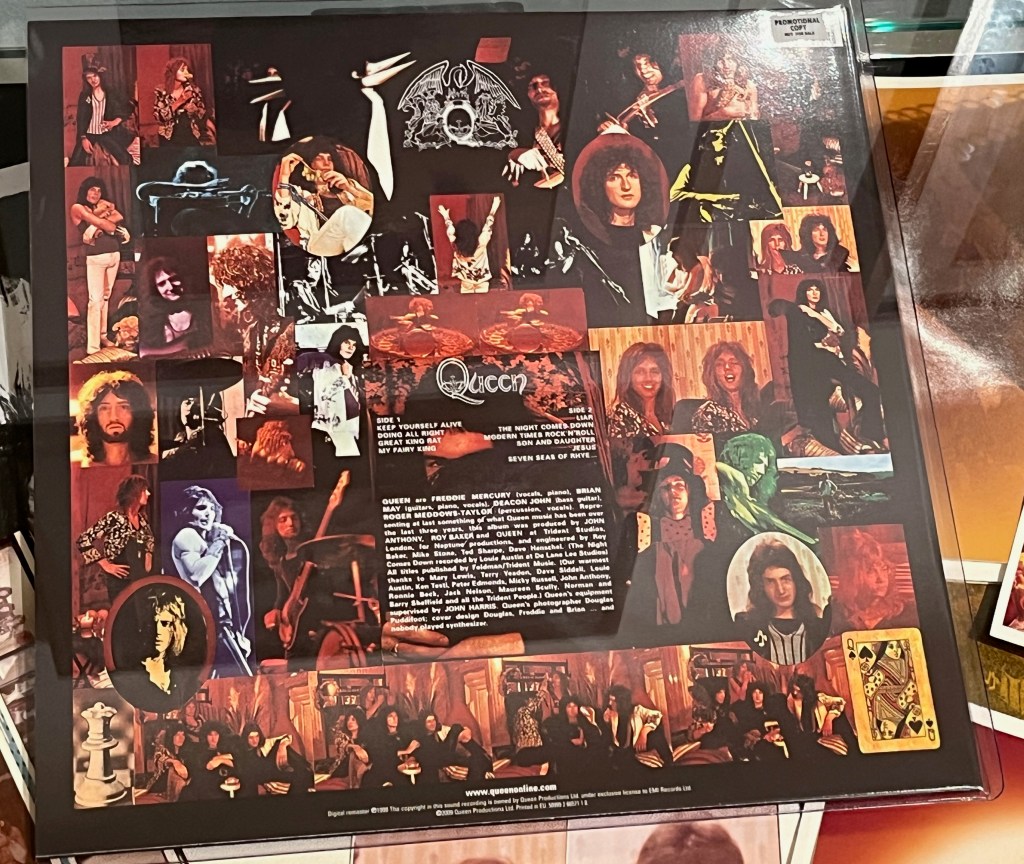 The back of Queen's debut album, with a collage of many photos of the band members surrounding a box with the track listing and credits.