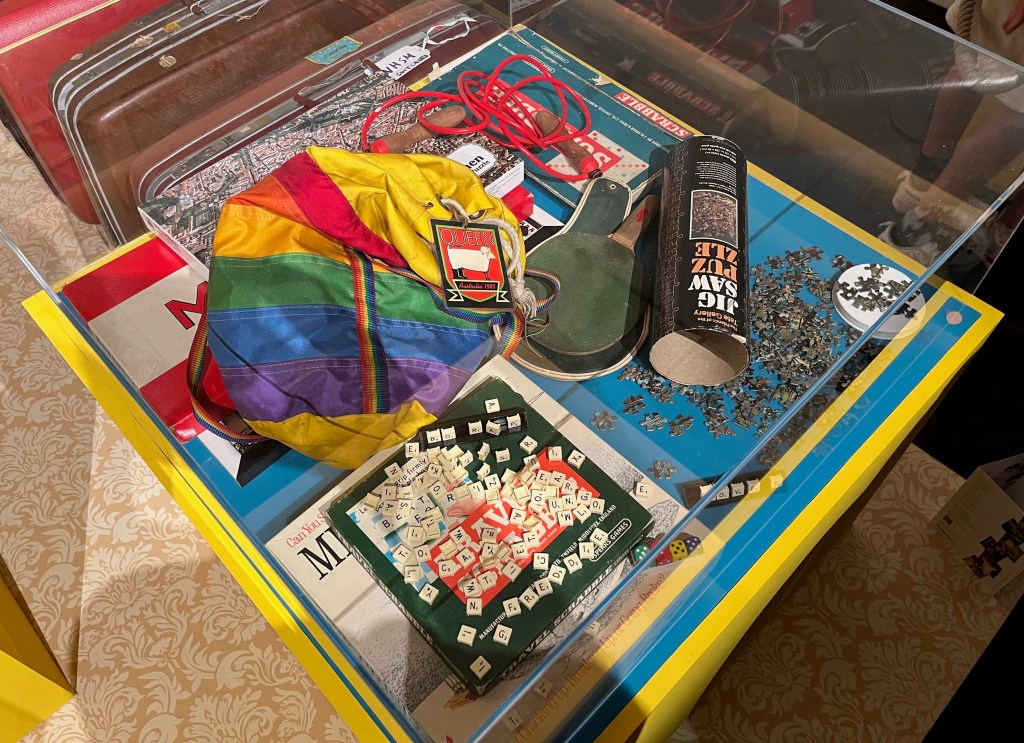 A collection of games and puzzles belonging to Freddie Mercury, including standard and travel versions of Scrabble, the Monopoly board game, a board game about surviving a mid-life crisis, two jigsaw puzzles, and a rainbow canvas duffel bag with a ping pong bat, two skipping ropes and a backstage pass for Queen's Australian tour in 1985.