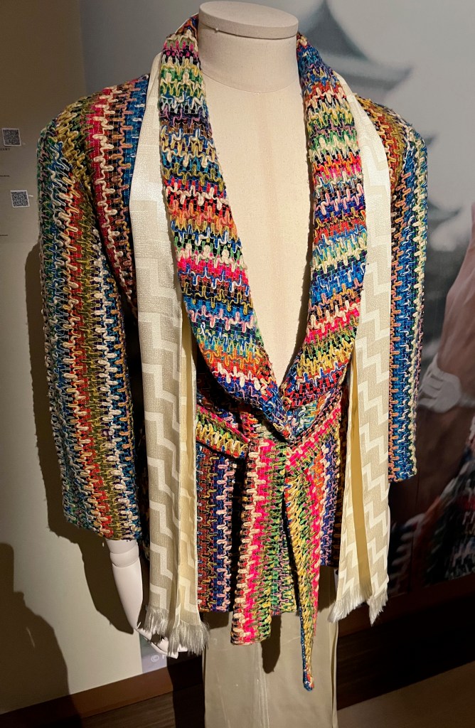 A loose-fitting brightly multi-coloured jacket with a weaved pattern, patch pockets at the hips and a matching self-tie belt.