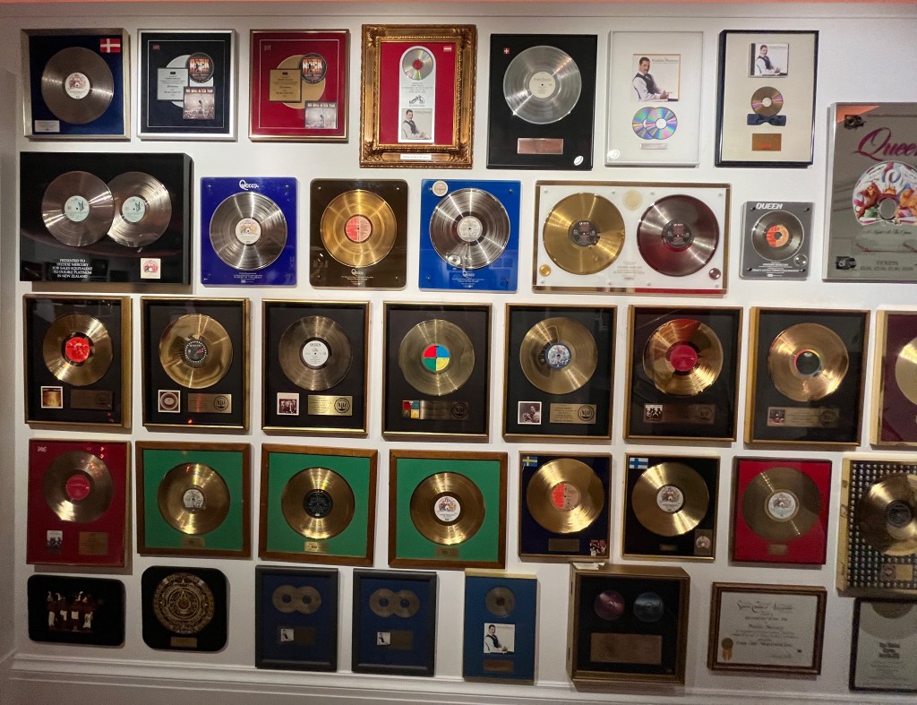 A wall filled with disc sales awards for Queen and Freddie Mercury albums and singles.